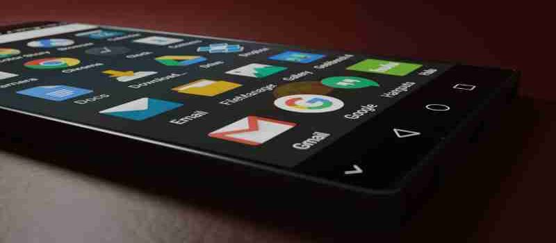 Close-up of a smartphone displaying various app icons in a low-light setting., tags: die den alltag - pexel