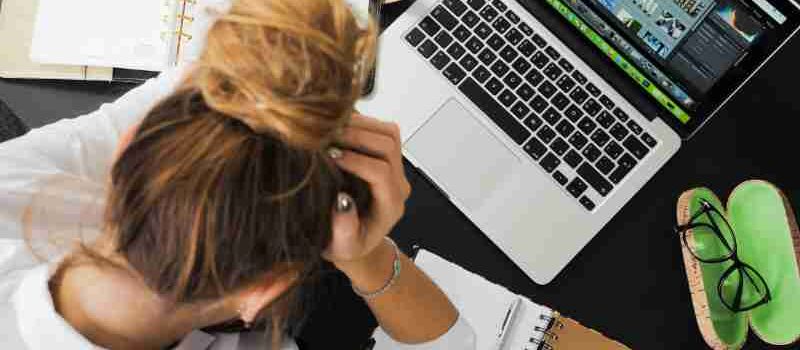 Overhead view of a stressed woman working at a desk with a laptop, phone, and notebooks., tags: zu und - pexel