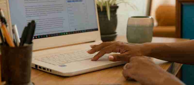 Hands typing on a laptop on a desk indoors with a mug and phone nearby., tags: moderne - pexel